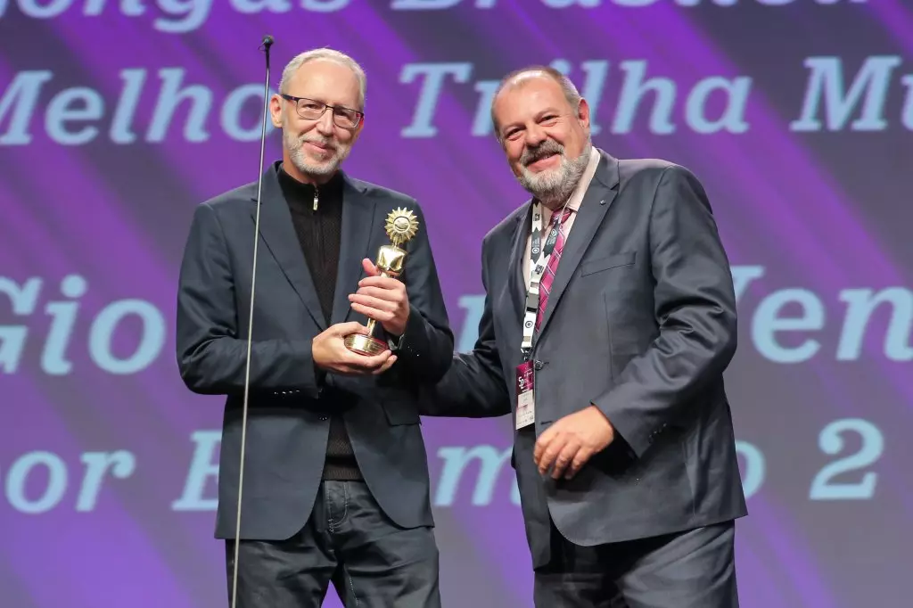 14495 | 17/08/2024 - 52º Festival de Cinema de Gramado - Giovanni Venosta recebe o prêmio de melhor trilha músical por “Estômago 2: O Poderoso Chef”, entregue por Jeferson Furstenau, diretora da Kia Sun Motors | Foto oficial: Edison Vara/Agência Pressphoto